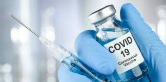 Healthcare cure concept with a hand in blue medical gloves holding Coronavirus, Covid 19 virus, vaccine vial