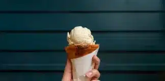 Scoop of sweet ice cream on croissant cone with wooden dark green wall background.